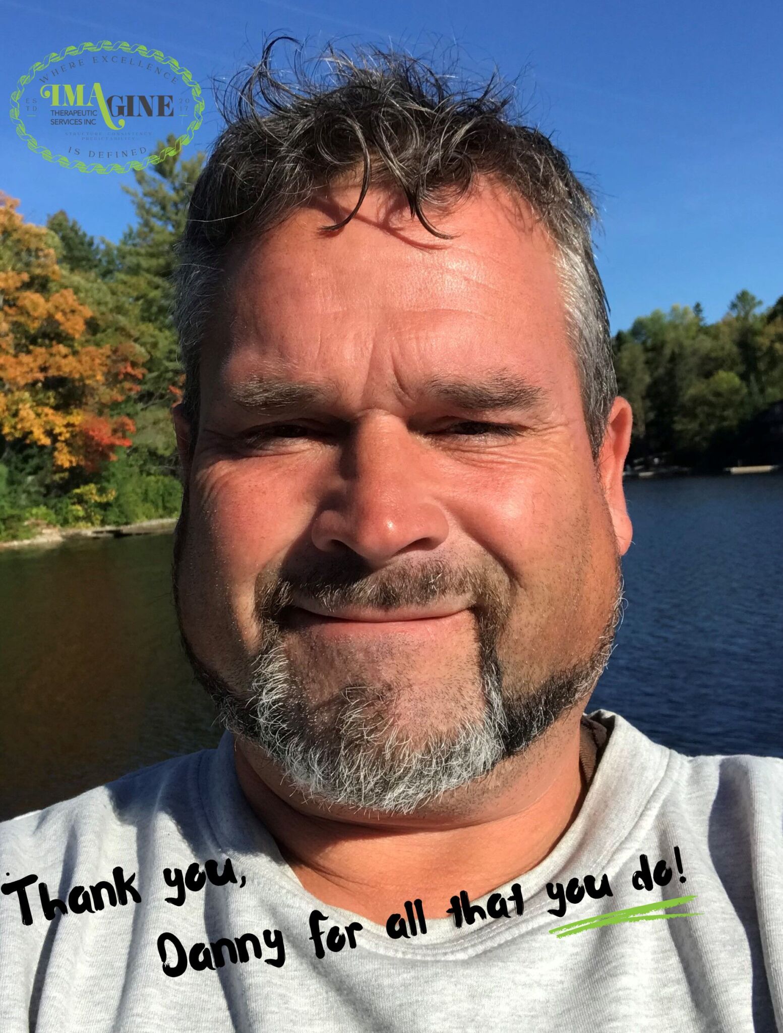 a selfie of Danny with a beautiful Ontario lake and trees behind him.